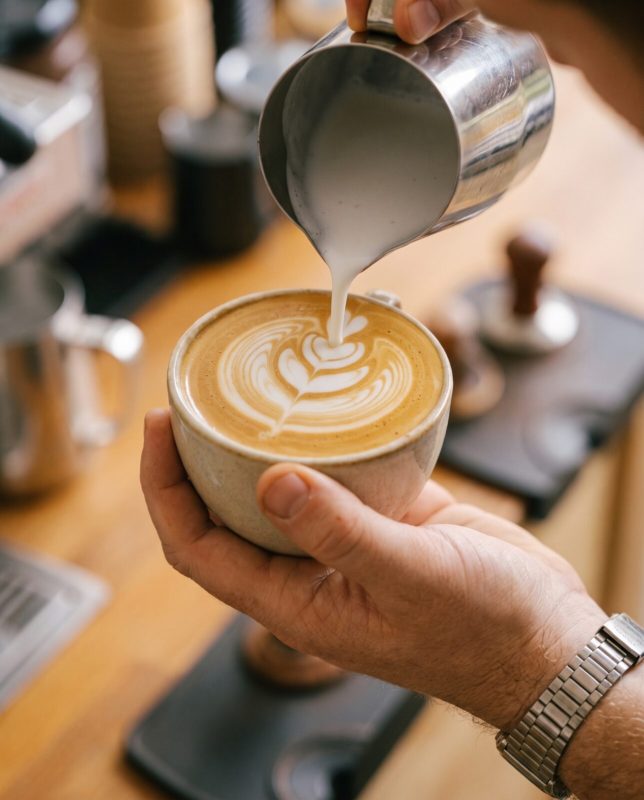 Close-up of a barista pouring a latte rosetta at a JoyBlast event in Greenville, SC