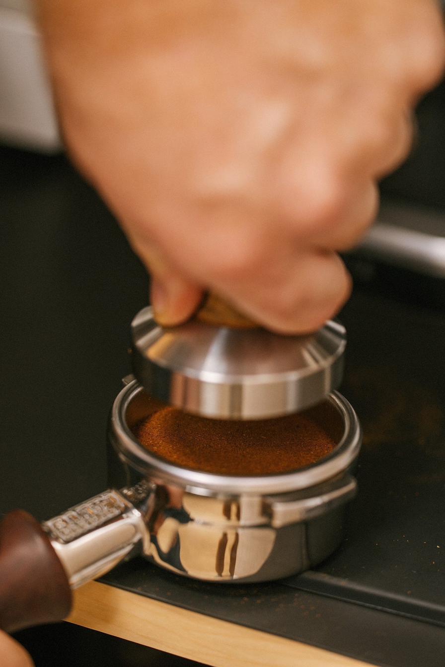 Barista tamping fresh espresso grounds