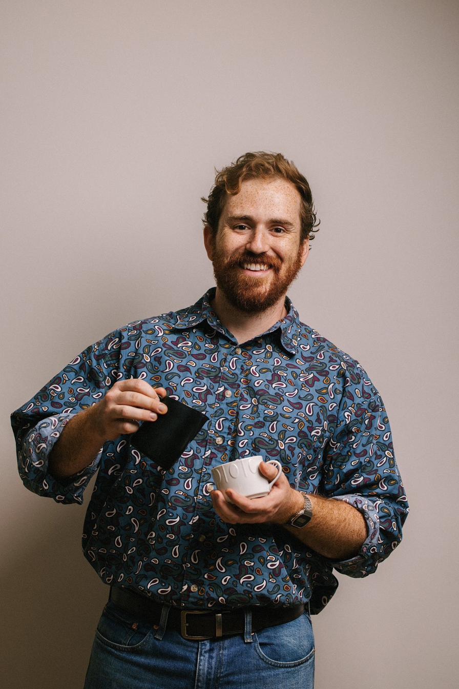 Luke Schneider of JoyBlast Coffee smiling while pouring a latte
